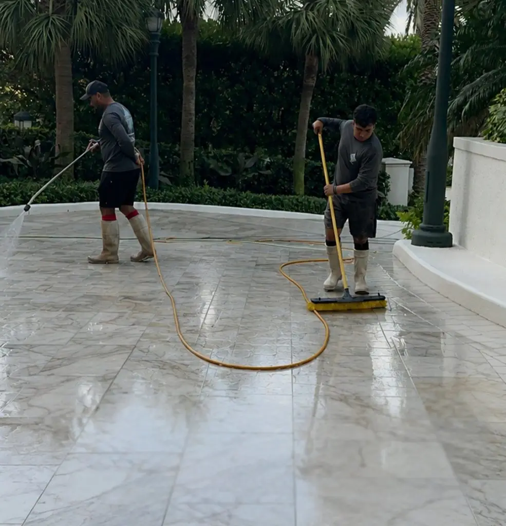 Team cleaning a white marble pool deck